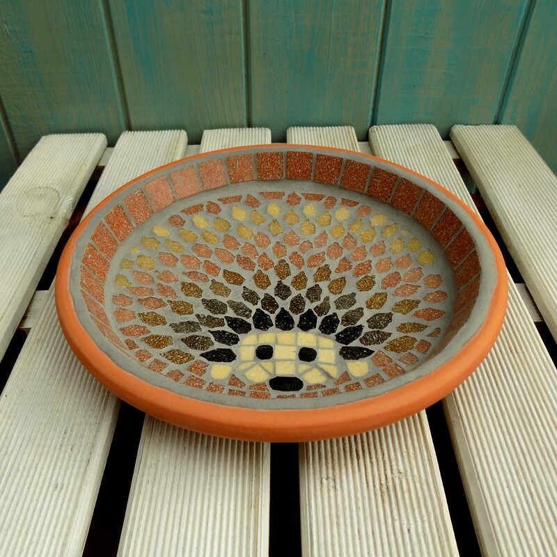 A mosaic bird bath with a design of a hedgehog made with shades of brown