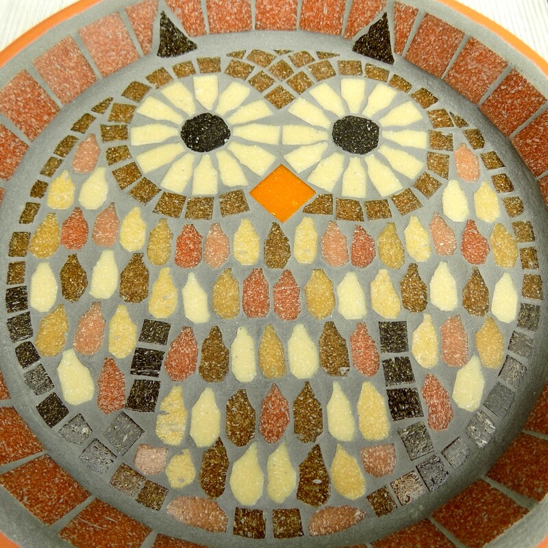 A mosaic garden birdbath with a design of a tawny owl made with browns, terracotta and cream tiles.