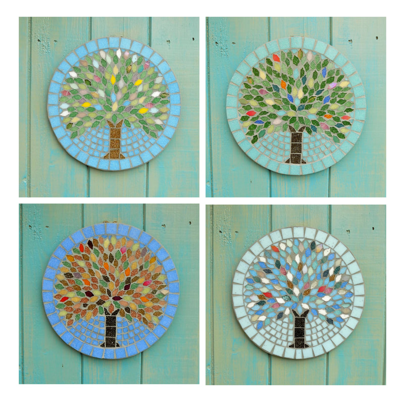 A set of hanging garden plaques with a tree design on each with the colours of that season used in the tiles for the leaves